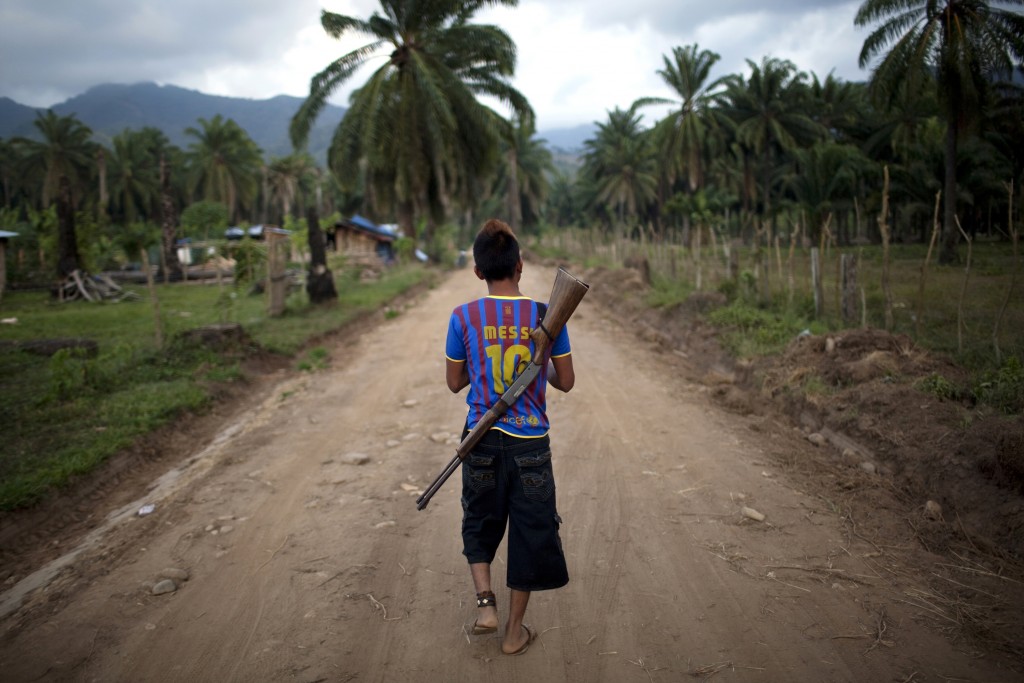 In this May 5, 2012 photo, Enrique Martinez,17, patrols in "La Confianza" peasant model city, Bajo Aguan, Honduras. Peasants from MUCA (Movimiento Unificado Campesino del Bajo Aguan) occupied around 7000 sq meters of productive land close to the city of Tocoa in the Valley of Bajo Aguan, eastern coast of Honduras in December, 2009. They operate a comercial production of african palm and they also stablished what they call a "peasant model city" called "La Confianza" where more than 300 hundred families live. Since then an open conflict between them and the alleged owner of the land, Miguel Facussé, one of the most powerful businessmen in Honduras has left more than 60 people dead including peasants, security guards, a journalist and members of the Honduran national police. (AP Photo/Rodrigo Abd)