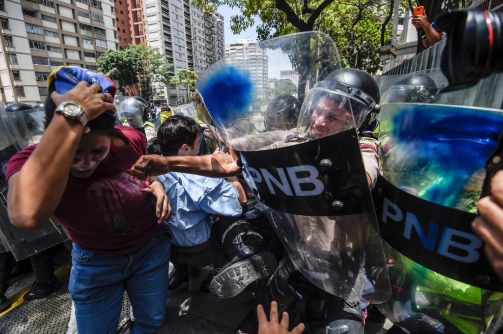 Venezuela's opposition activists scuffle with riot police during a protest against Nicolas Maduro's government in Caracas on April 4, 2017.  Protesters clashed with police in Venezuela Tuesday as the opposition mobilized against moves to tighten President Nicolas Maduro's grip on power. Protesters hurled stones at riot police who fired tear gas as they blocked the demonstrators from advancing through central Caracas, where pro-government activists were also planning to march. / AFP PHOTO / JUAN BARRETO        (Photo credit should read JUAN BARRETO/AFP/Getty Images)